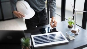 Renewable energy professional holding a hard hat and signing a digital tablet alongside solar panel and wind turbine models representing a power purchase agreement and wheeling agreement in South Africa