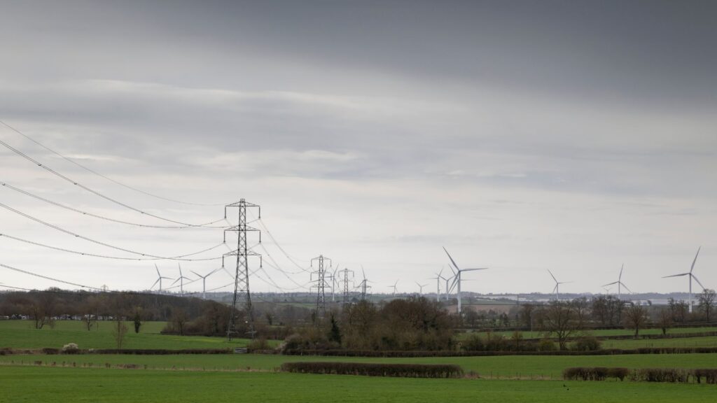 Wind turbines and high-voltage transmission pylons illustrating how wheeled energy travels from an independent power producer through the national grid to commercial offtakers in South Africa