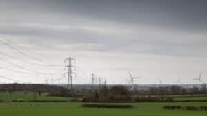 Wind turbines and high-voltage transmission pylons illustrating how wheeled energy travels from an independent power producer through the national grid to commercial offtakers in South Africa